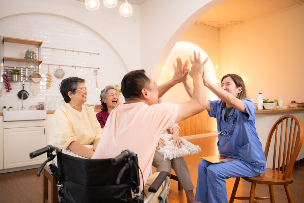 Group of elderly and senior man in wheelchair with nurse at nursing home Play a fun game of hitting each other's hands. Elderly people in nursing home concept