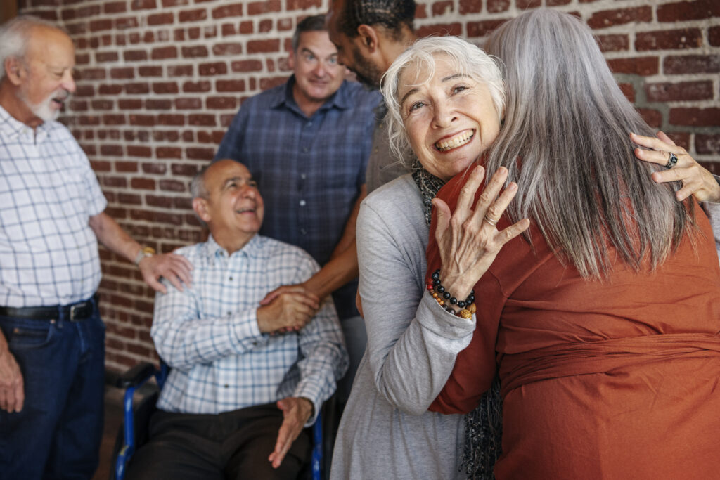 Happy elderly man on a wheelchair talking with friends