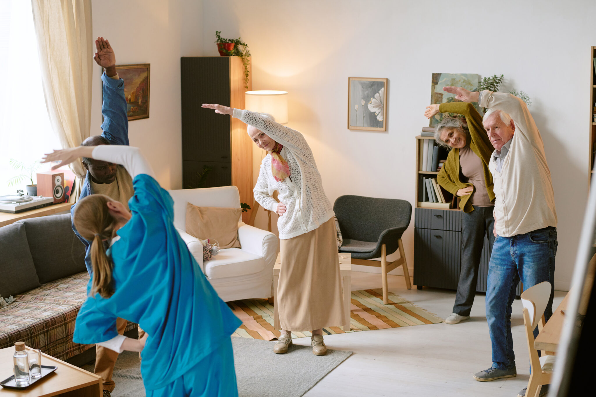 High angle shot of unrecognizable nurse helping elderly people with stretching, they standing in circle and doing side bends in nursing home